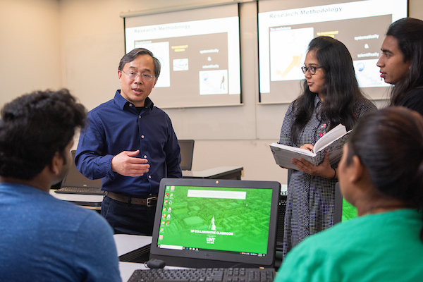 A faculty member with a group of students in a classroom