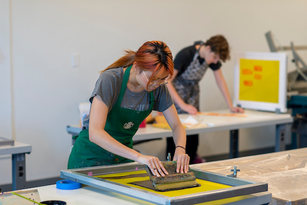 Students in aprons at work in a screenprinting studio
