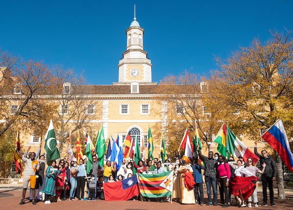Students wave international flags in front of Hurley Administration building