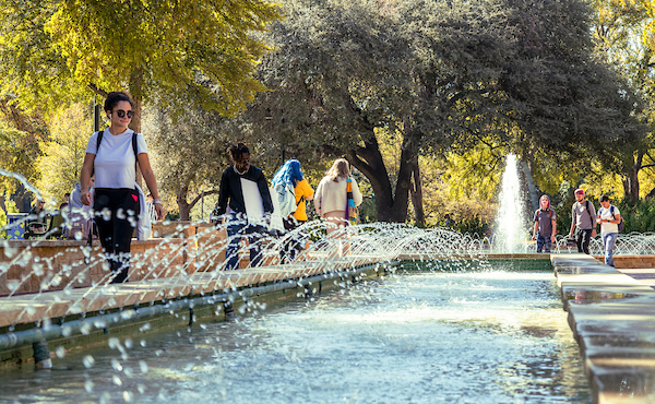 Students walk beside the Library Mall fountain 