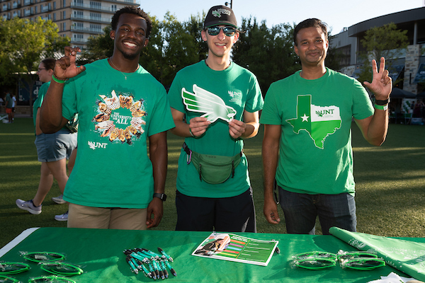Students hold UNT merch and make the "claw" hand sign