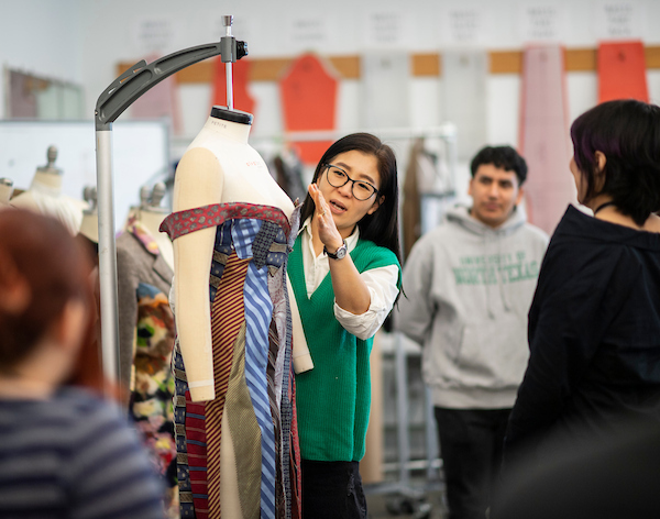 A fashion instructor demonstrates a point on a dressed mannequin