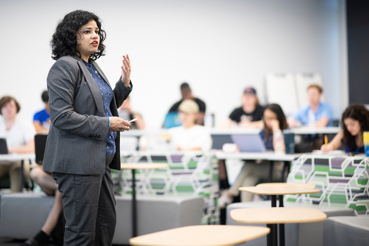 A lecturer in a business suit presents to a classroom of students