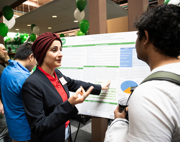 Two students discuss a research poster at an on-campus event