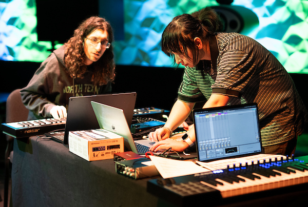 Students work with keyboards and laptop during a stage performance