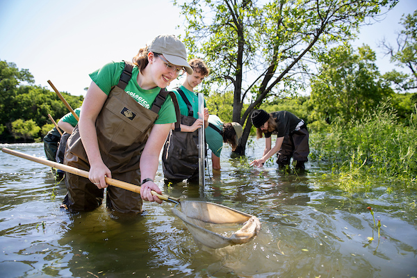 Students in waders conduct research on pond water