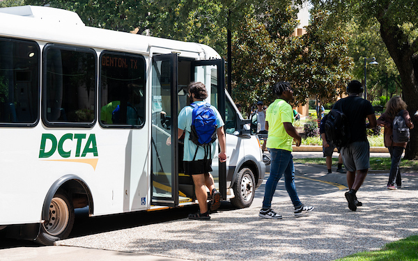 Students enter and exit a DCTA bus on campus