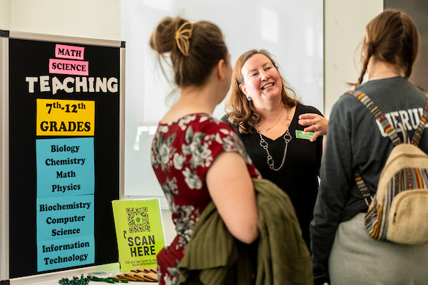 A recruitment representative speaks with event attendees about teaching 7th-12th grade math and science
