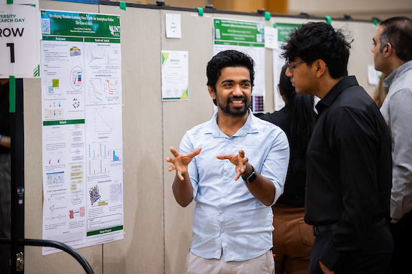 Two students discuss a research poster