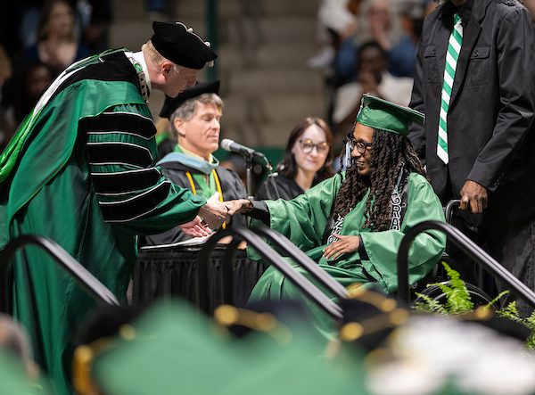 The president shakes hands with a student at commencement
