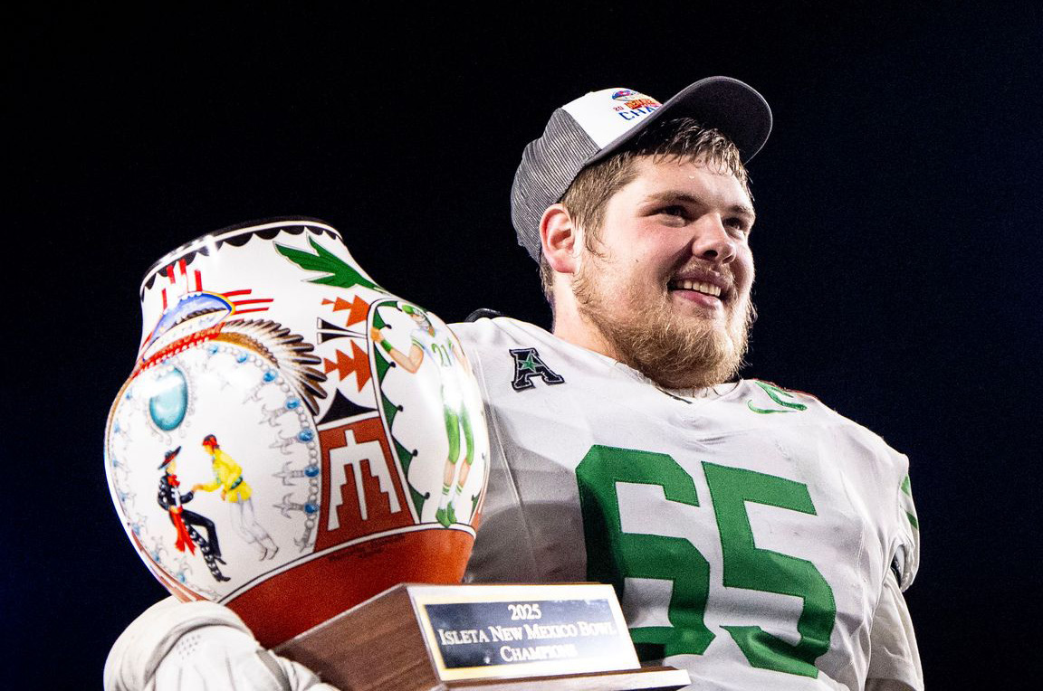 A student football player poses with a 2025 New Mexico championship trophy