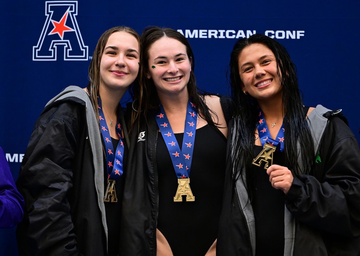 Three swim team athletes pose with their medals