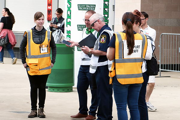 Event support staff in orange vests assist DATCU stadium visitors